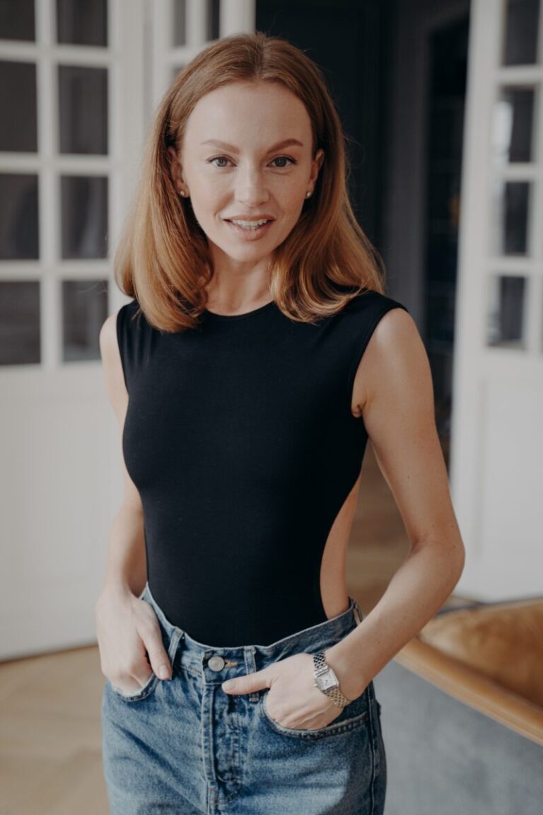 Menokind - Menokinds historie Elegant lady in fashionable slim fit black bodysuit and jeans in luxurious apartment.