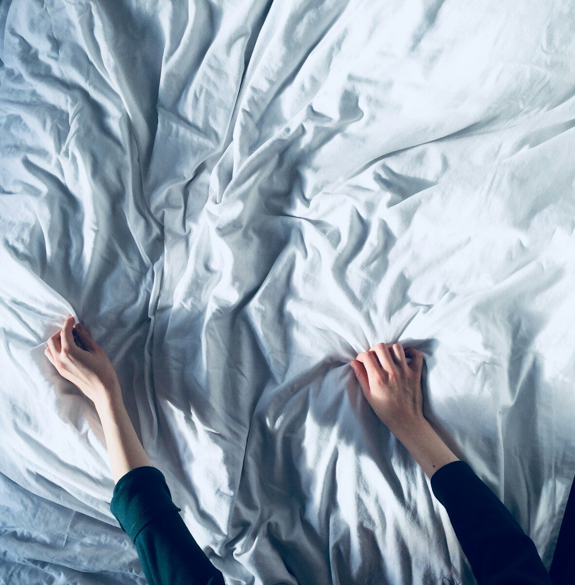 Menokind - Hormonel kvalme — når skift i hormoner får maven til at gå i bølgegang person holding white bedspread