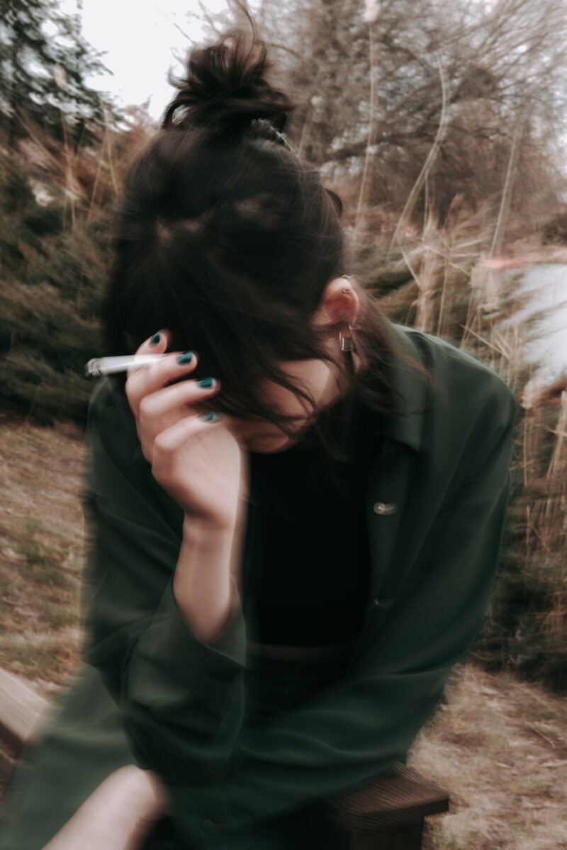 Menokind - Hedeture — når kroppen koger uden varsel a woman sitting on a bench smoking a cigarette