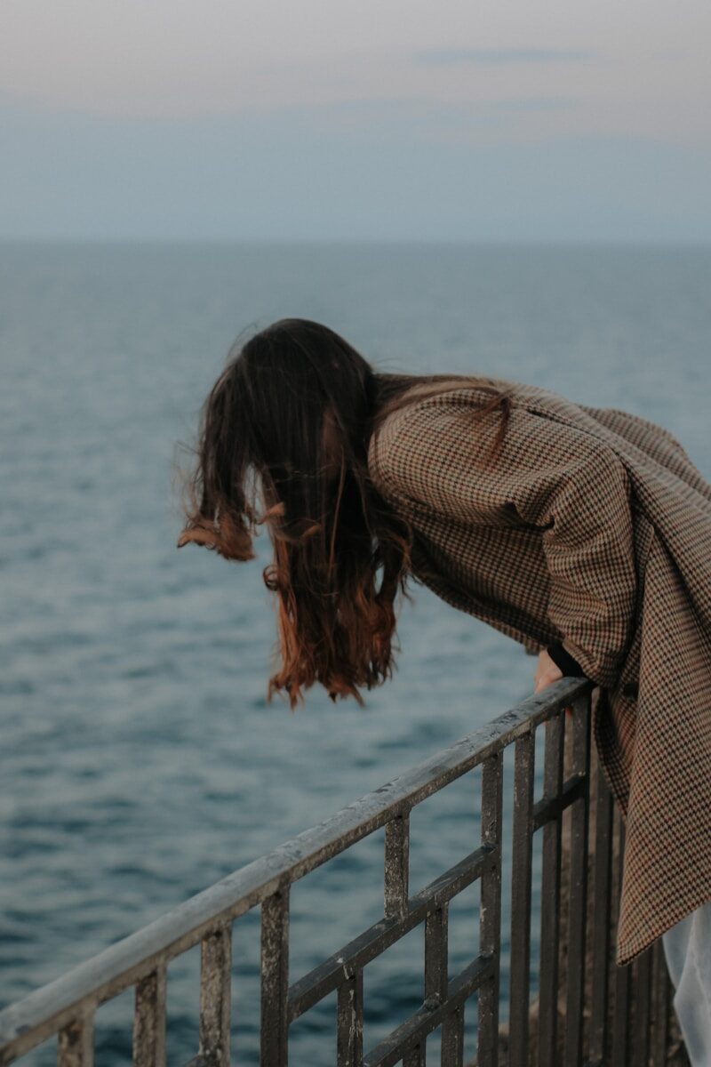 Menokind - Irritabilitet — det blinde raseri, som kommer, sejrer og efterlader alle desorienterede a woman leaning over a railing near the ocean