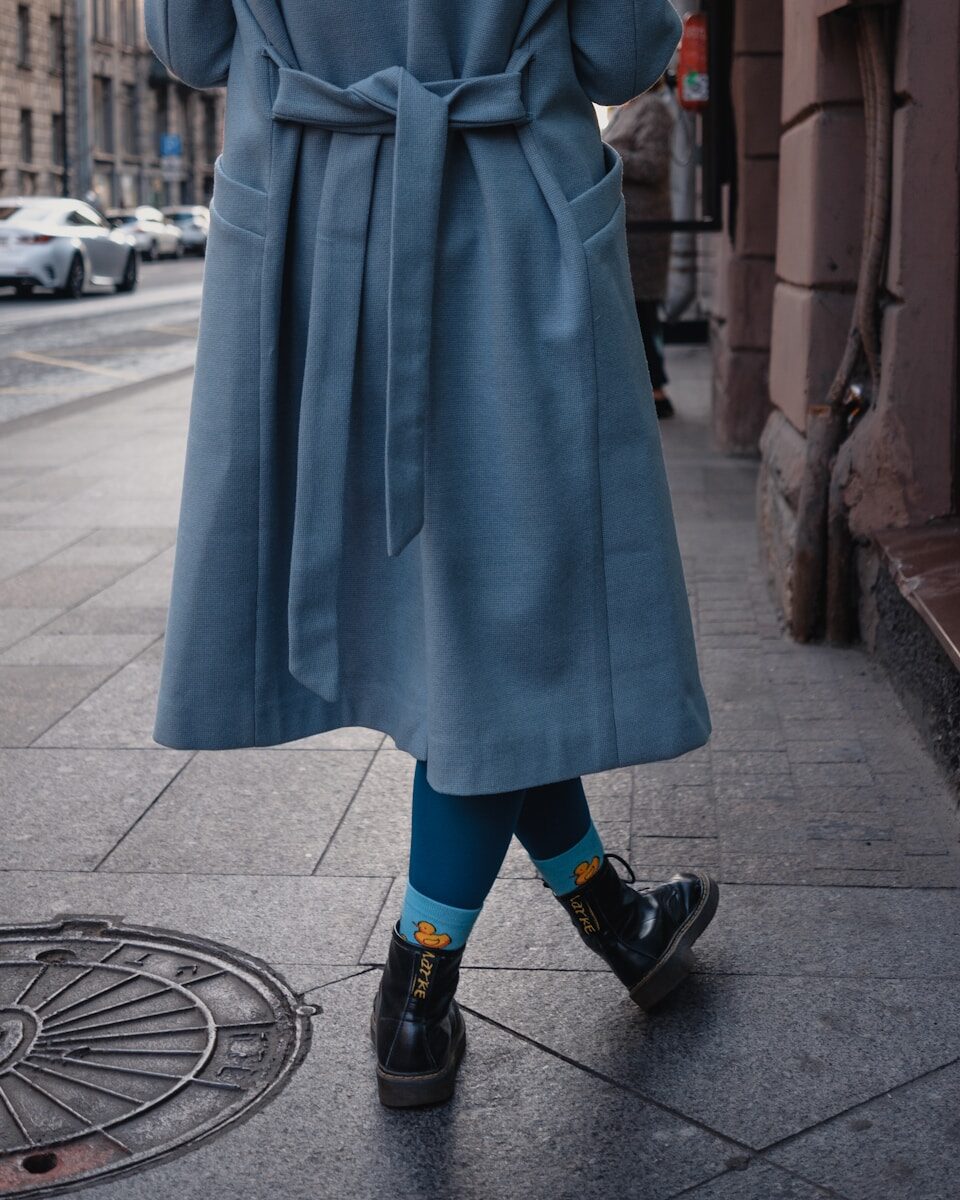 a woman in a blue coat is walking down the street