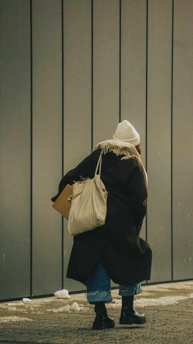 A woman walking down a street carrying a bag